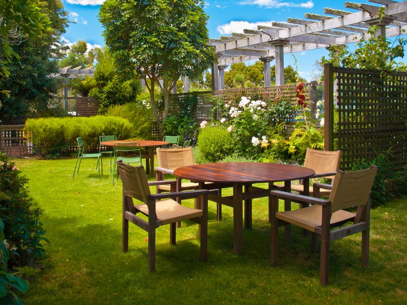 jardin con cuatro sillas y una mesa con flores alrededor